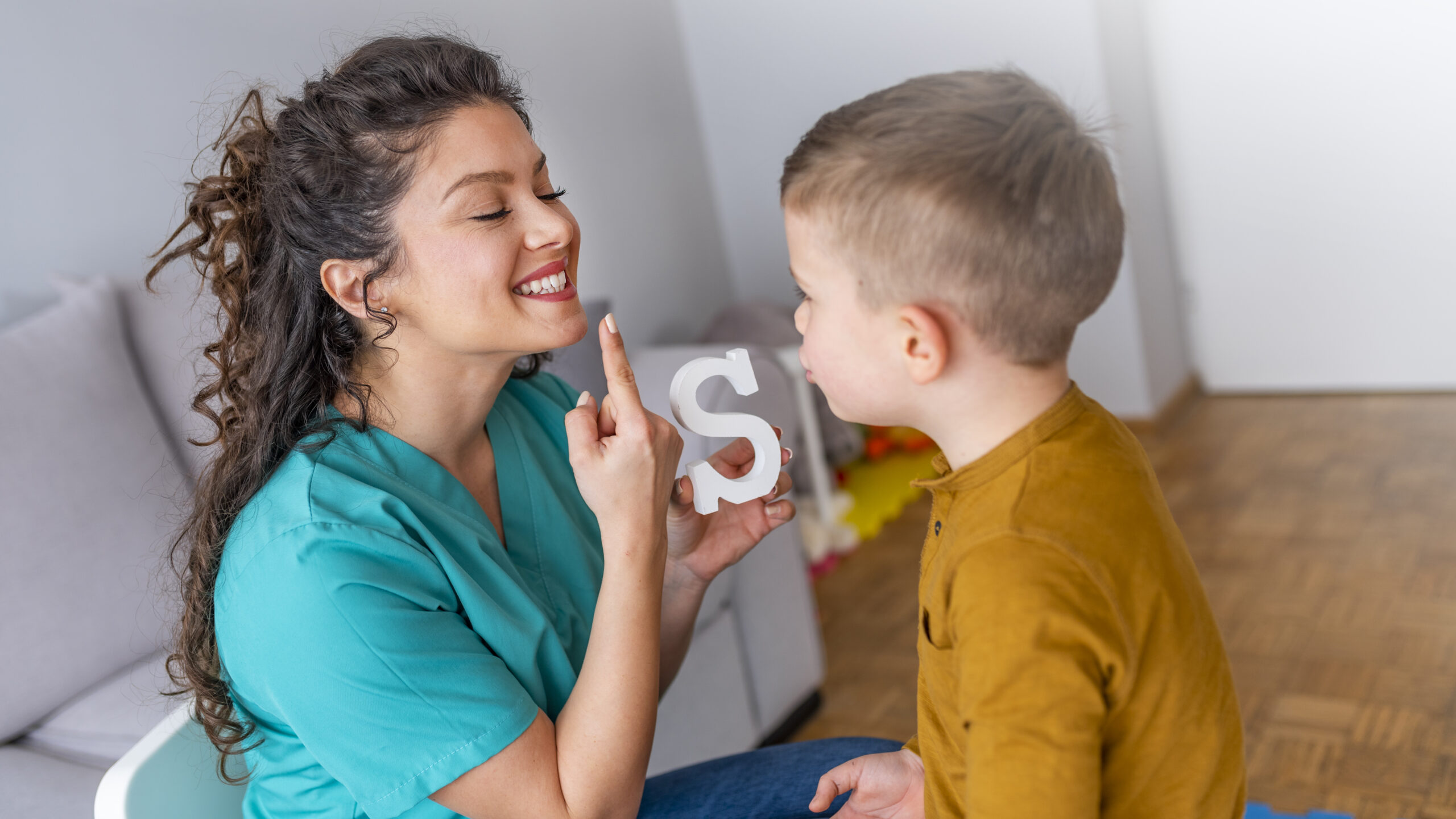Speech therapist and little patient training articulation. Speech therapist teaches the boys to say the letter S. Shot of a speech therapist during a session with a little boy